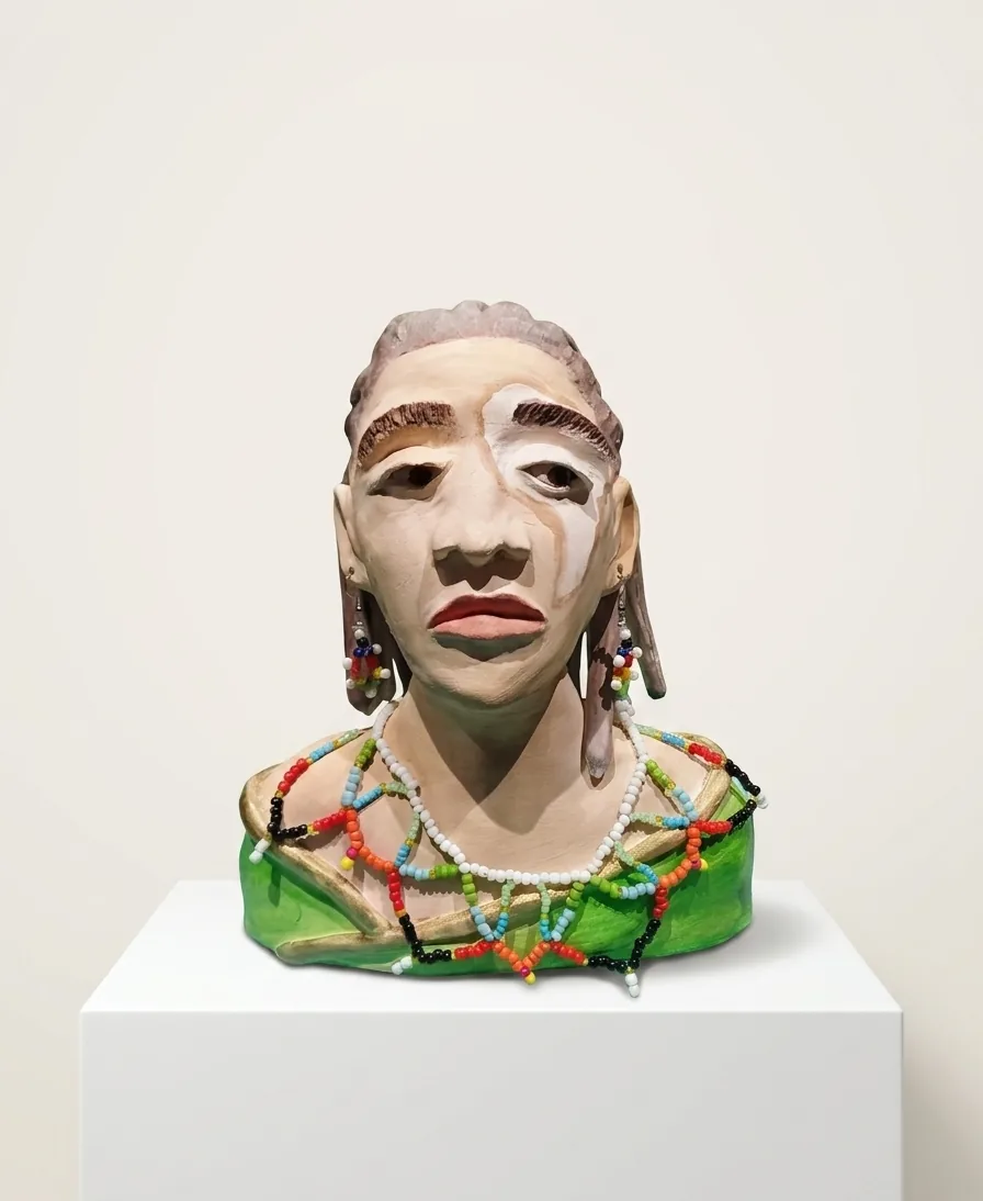 Beaded Bust — a hand-built ceramic bust in a green wrap, wearing strung glass-bead necklaces and earrings, on a white plinth.