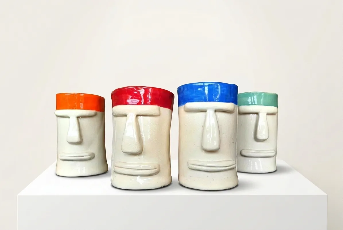 Moai Tumblers — four cream tumblers moulded as Easter Island faces, each dipped in orange, red, blue or green glaze.