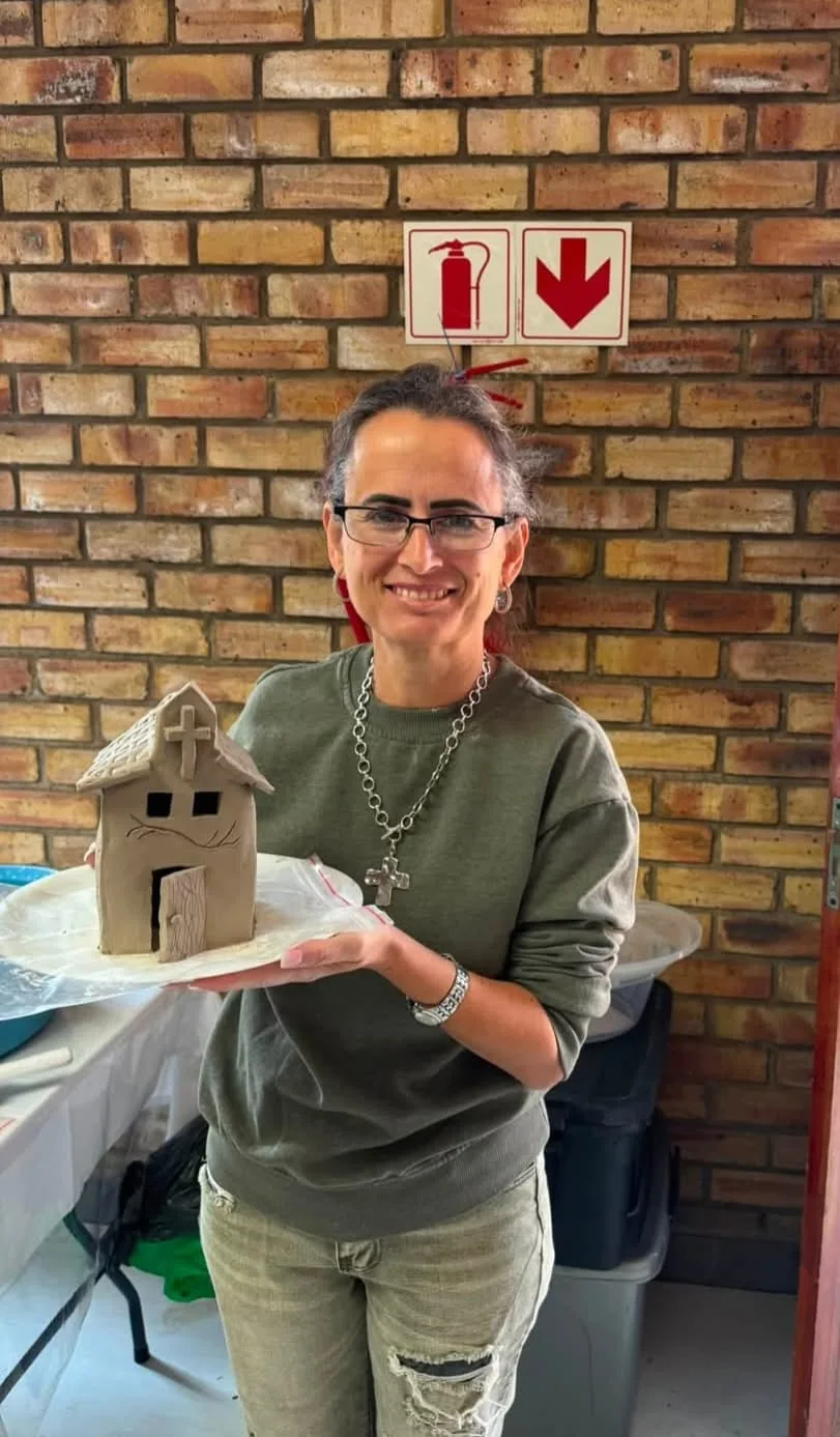 Saartjie Gerber glimlag met 'n handgeboude kleikerkie wat sy by 'n werkswinkel gemaak het.